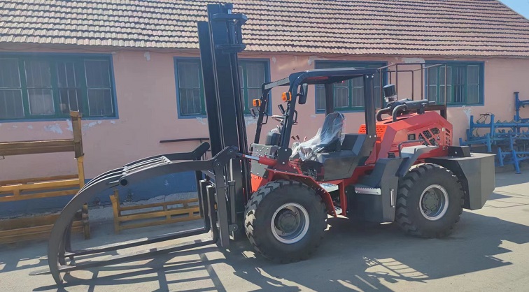 A photo shows a custom forklift moving wooden crates up a hillside. The forklift is a Kaystar Landtiger35Pro model, which has an articulated four-wheel drive function, and is equipped with a special upper clamp attachment and a 1.97-meter-long fork. The upper holding clamp attachment can fix the goods and prevent the goods from falling. The forklift driver in the photo is wearing safety clothing and operating the forklift.