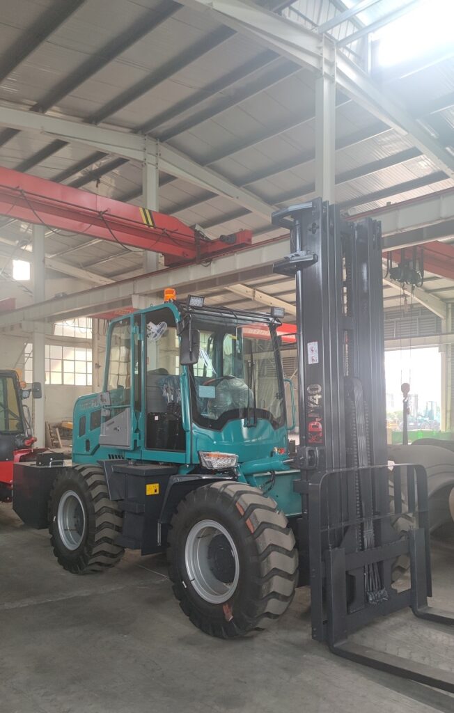 A blue 4-ton articulated off-road forklift with a 3-stage free lifting mast and a five-way hydraulic valve parked on a dirt road.