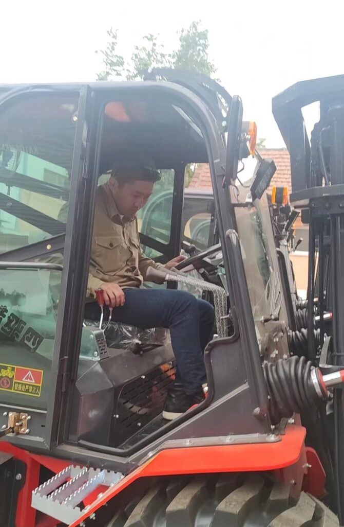 A photo of Mr. Akylbek sitting on the driver’s seat of the Landtiger35Pro articulated 4WD forklift at Kaystar factory, smiling and giving a thumbs up.