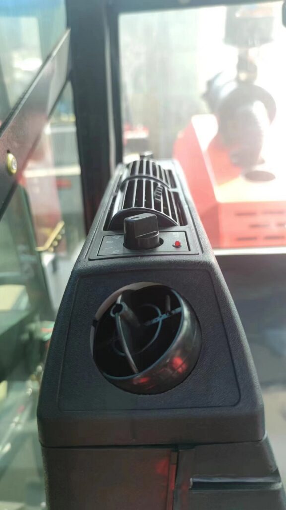 An outdoor forklift made in China, with a closed cab and air conditioner installed, and a photo of the air outlet of the air conditioner in the cab.