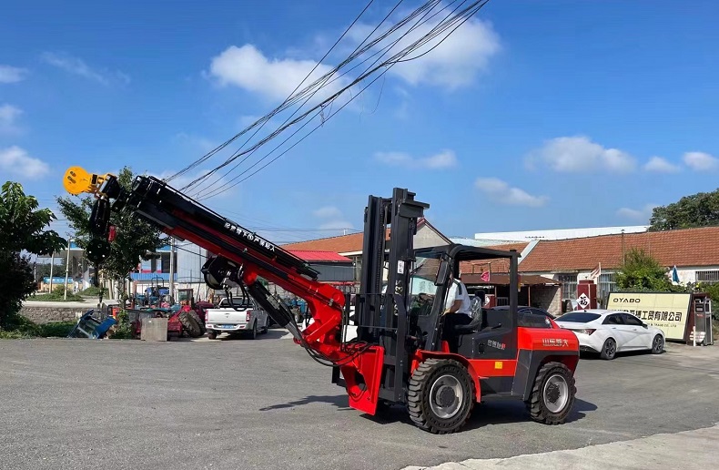 A picture of a red Kaystar Pioneer35 4x4 forklift with a red and black fly jib attached to its front. The fly jib is extended to its maximum length of 12 meters and has a hook at its end. The background shows a blue sky and some trees.
